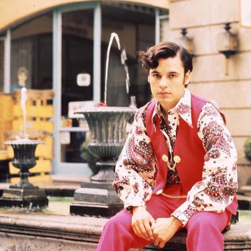 El cantante Juan Gabriel sentado en un muro